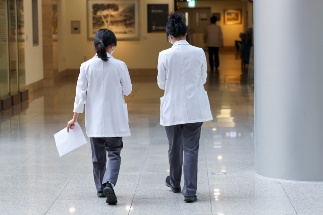 의대 교수들이 사직서를 제출한 지 한 달이 다 되어가며 무더기 사직이 현실화할 수 있다는 우려가 제기되고 있는 가운데 23일 오전 서울 시내 한 대학병원에서 의료진이 이동하며 대화를 나누고 있다. <연합뉴스>